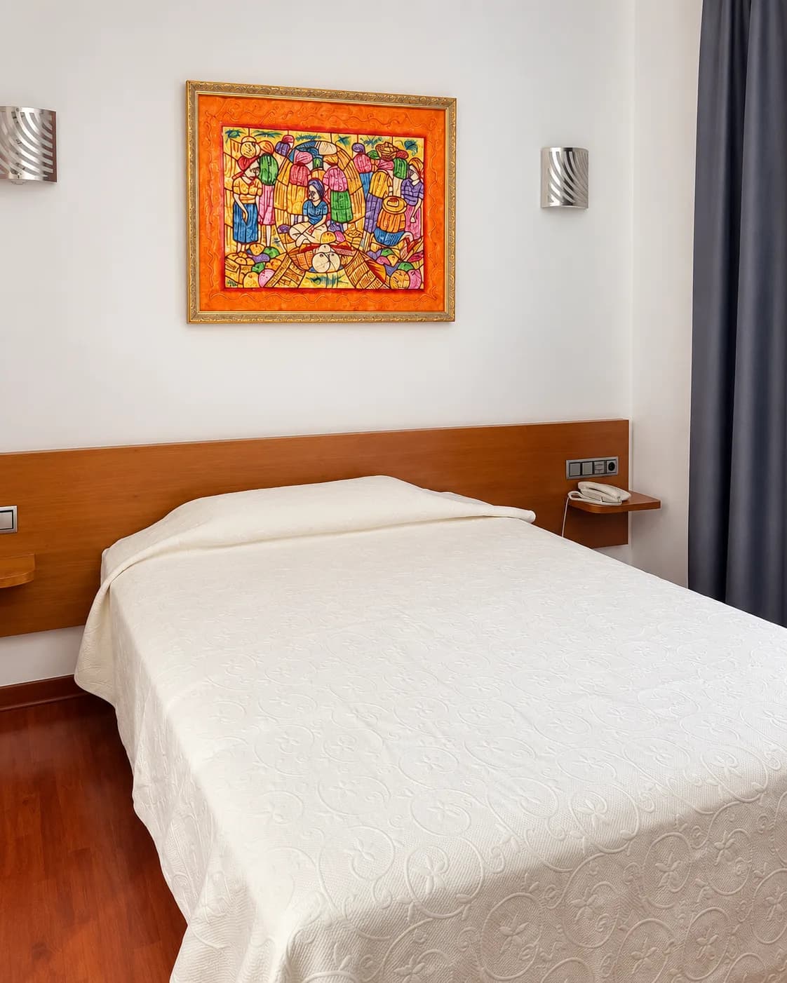 Habitación doble luminosa con cama matrimonial, cabecero de madera y cuadro colorido en Hotel Plaza Inn en España